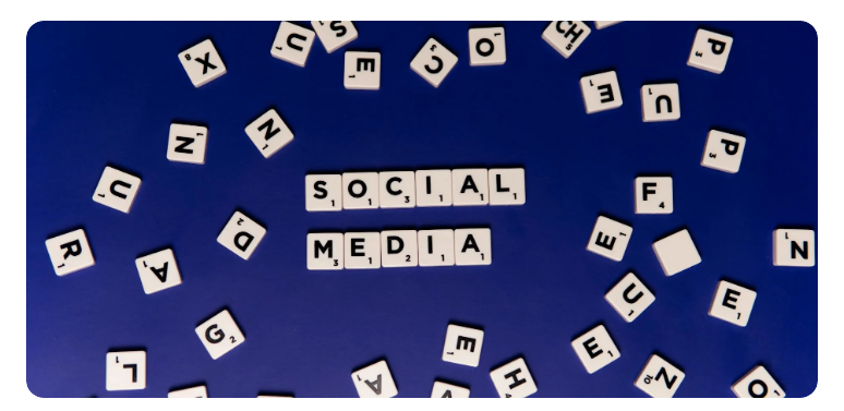 Scrabble tiles spelling out 'SOCIAL MEDIA' on a blue background with scattered tiles around